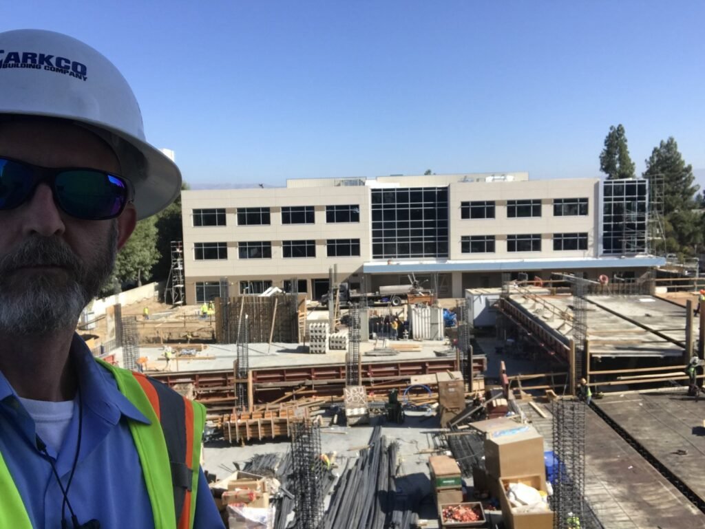 Peter Pendleton on a deck with rebar staged and an office building behind