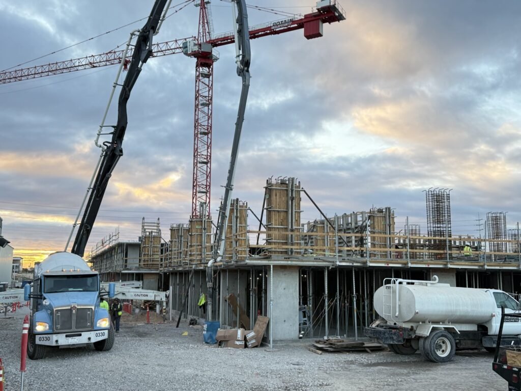 Concrete pour day with boom pump and tower crane on a multifamily project